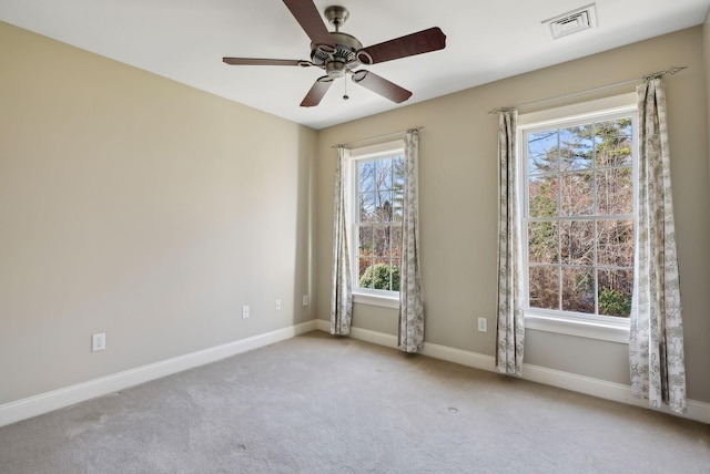 carpeted empty room featuring visible vents, a ceiling fan, and baseboards