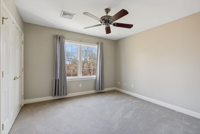 carpeted spare room with visible vents, ceiling fan, and baseboards