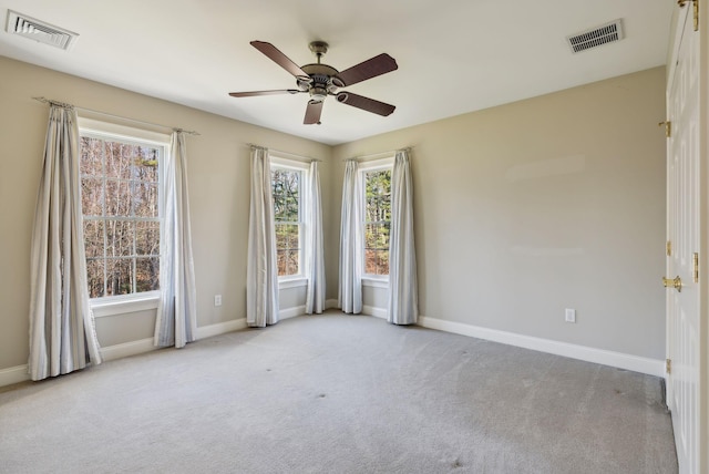 spare room with visible vents, carpet flooring, baseboards, and ceiling fan