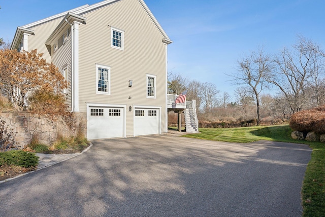 view of property exterior featuring stairs, a garage, and driveway