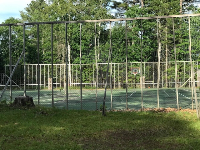 view of tennis court with a yard