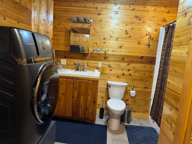 bathroom featuring washer / clothes dryer, toilet, wooden walls, and vanity