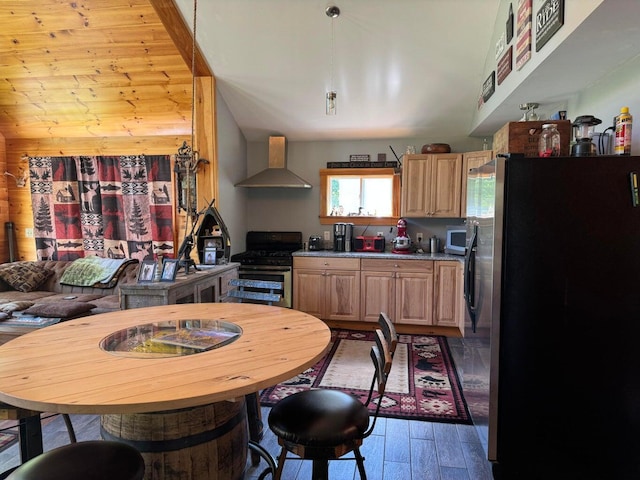 kitchen with light hardwood / wood-style flooring, wall chimney range hood, appliances with stainless steel finishes, and light brown cabinets