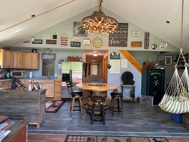 dining space with dark wood-type flooring, high vaulted ceiling, sink, and a notable chandelier