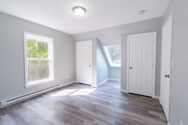 12 Sunset Ln, Otis, ME 04605 - unfurnished bedroom featuring baseboards, baseboard heating, wood finished floors, and vaulted ceiling with skylight