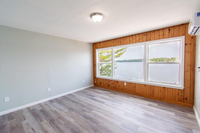 12 Sunset Ln, Otis, ME 04605 - unfurnished room featuring light wood finished floors, a wall mounted air conditioner, baseboards, and a water view