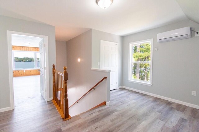 12 Sunset Ln, Otis, ME 04605 - interior space with a wall mounted air conditioner, baseboards, an upstairs landing, and wood finished floors