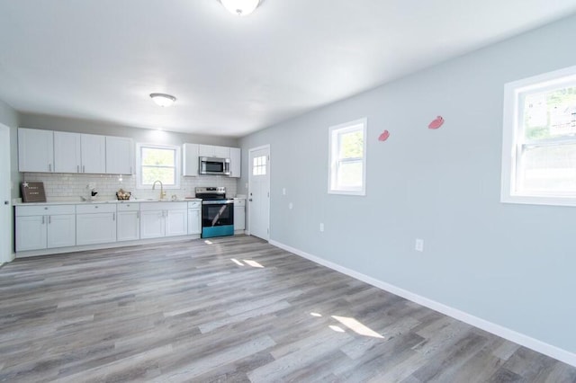 12 Sunset Ln, Otis, ME 04605 - kitchen featuring tasteful backsplash, baseboards, light wood-type flooring, stainless steel appliances, and a sink