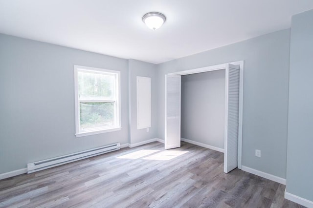 12 Sunset Ln, Otis, ME 04605 - unfurnished bedroom featuring a closet, a baseboard heating unit, baseboards, and wood finished floors