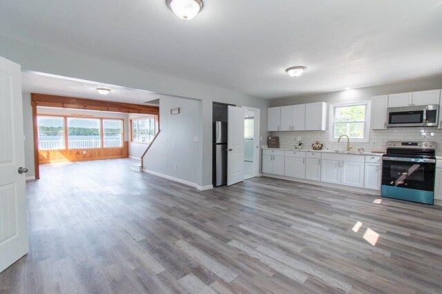 12 Sunset Ln, Otis, ME 04605 - kitchen featuring backsplash, open floor plan, appliances with stainless steel finishes, light wood-style floors, and a sink