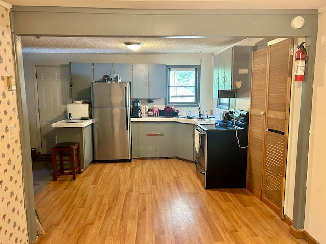 kitchen featuring appliances with stainless steel finishes, light hardwood / wood-style flooring, and a textured ceiling