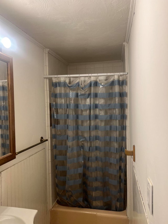 bathroom featuring ornamental molding, shower / bath combo with shower curtain, and a textured ceiling