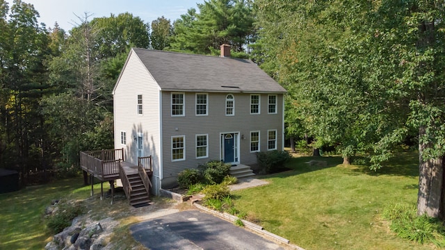 colonial-style house with a wooden deck and a front lawn