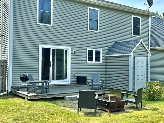 rear view of house featuring a wooden deck, a lawn, a storage unit, and an outdoor fire pit