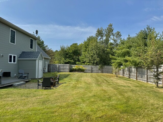 view of yard with a wooden deck, a storage unit, and an outdoor fire pit