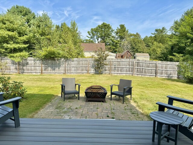 wooden terrace with a fire pit, a patio area, and a lawn