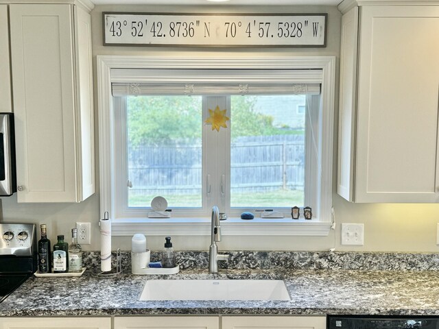 details with dark stone countertops, dishwashing machine, sink, and white cabinets