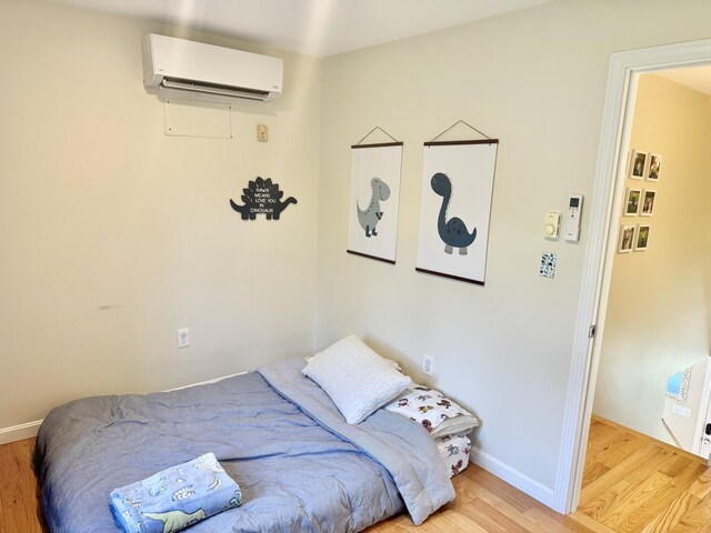 bedroom featuring light hardwood / wood-style floors and a wall mounted air conditioner