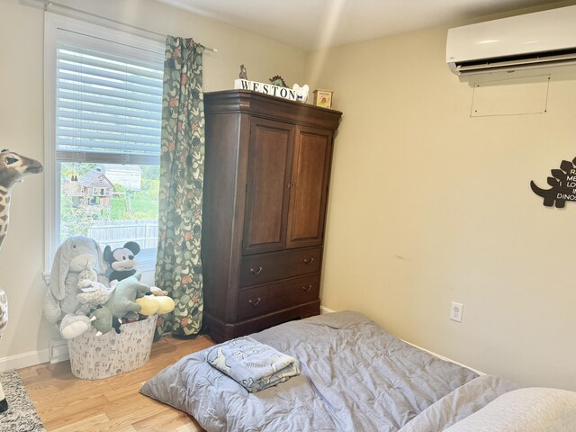 bedroom with light wood-type flooring and an AC wall unit