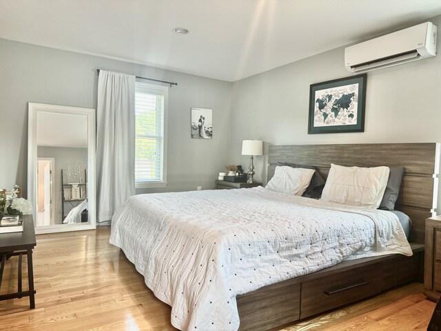 bedroom featuring light wood-type flooring and a wall unit AC