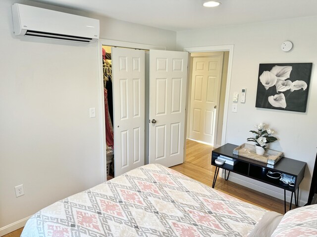 bedroom featuring a wall mounted AC, a closet, and wood-type flooring