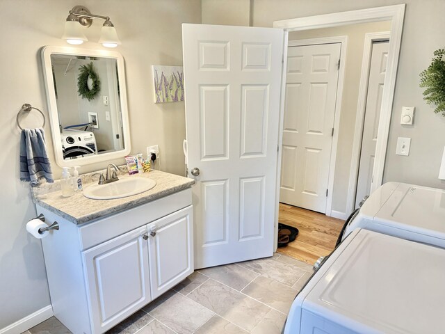 bathroom featuring washer and dryer, vanity, and hardwood / wood-style floors