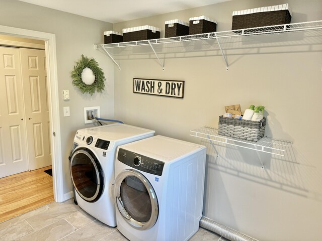 laundry area with independent washer and dryer and light hardwood / wood-style floors