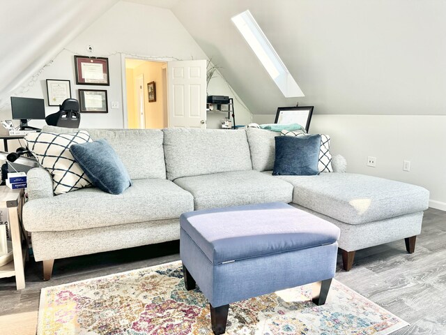 living room featuring hardwood / wood-style floors and vaulted ceiling with skylight