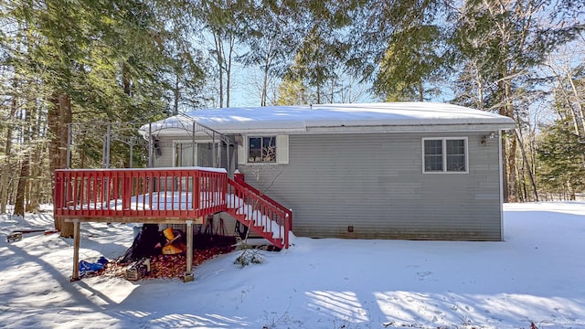 snow covered rear of property with a wooden deck