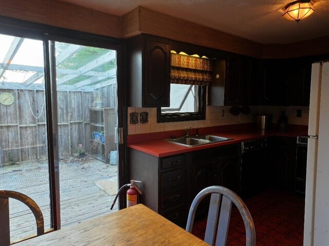 kitchen featuring dishwasher, dark brown cabinets, backsplash, and sink