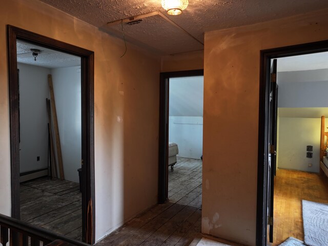 hall with a textured ceiling and wood-type flooring