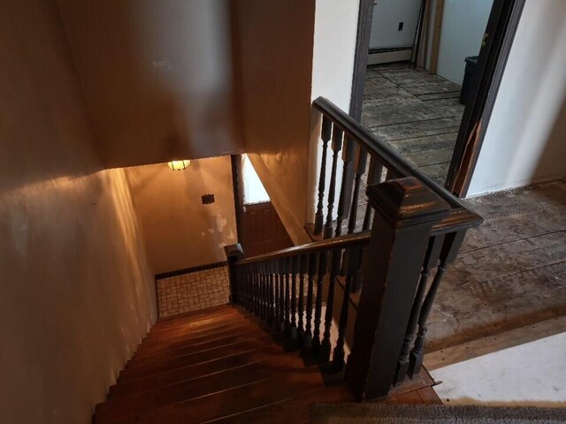 stairs featuring hardwood / wood-style floors and a baseboard heating unit