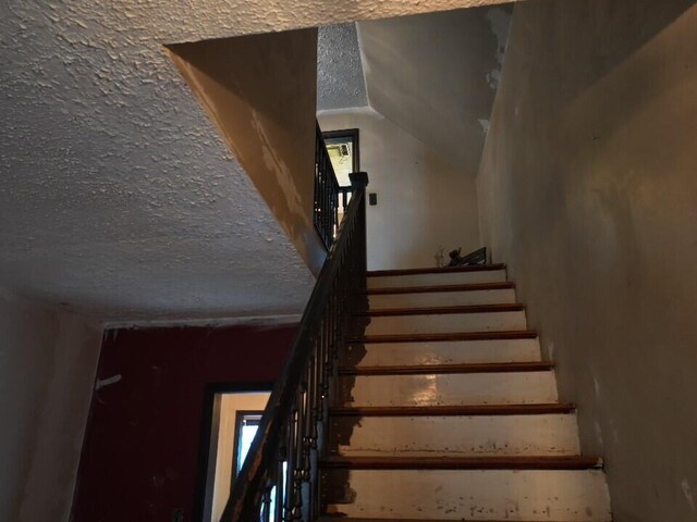 stairway featuring a textured ceiling