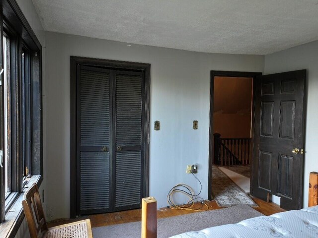 bedroom with a textured ceiling, a closet, and dark hardwood / wood-style flooring