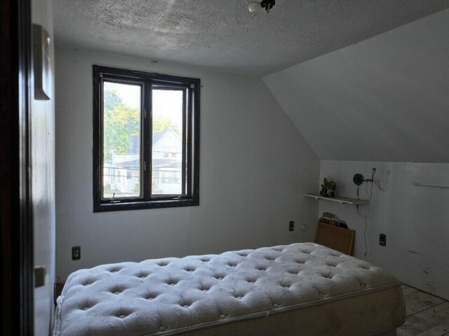 bedroom featuring a textured ceiling and lofted ceiling