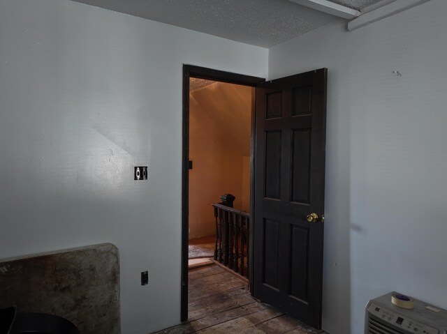 corridor with a textured ceiling and dark hardwood / wood-style floors