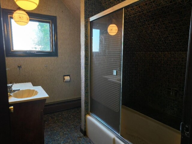 bathroom with a baseboard heating unit, shower / bath combination with glass door, and vanity