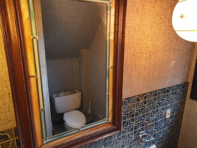 bathroom with a shower with door and toilet