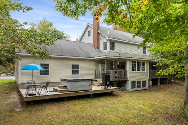 rear view of property with a yard, a wooden deck, and a hot tub