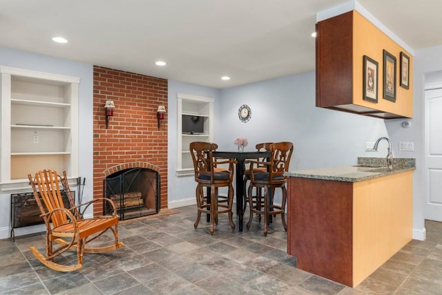 dining area with built in shelves, sink, and a brick fireplace