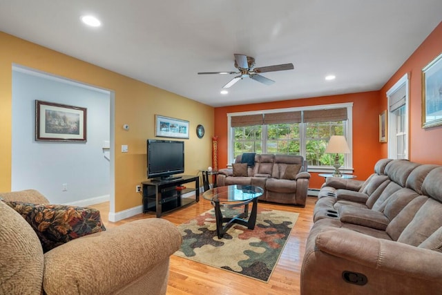 living room featuring baseboard heating, ceiling fan, and light hardwood / wood-style floors