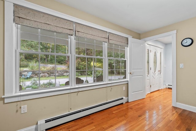 unfurnished room featuring plenty of natural light, light hardwood / wood-style floors, and a baseboard radiator