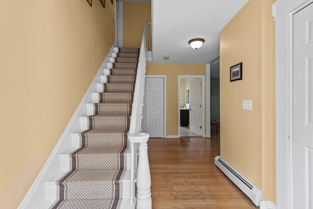 staircase featuring baseboard heating and hardwood / wood-style flooring