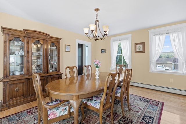 dining space featuring light wood-type flooring, a chandelier, and a baseboard radiator