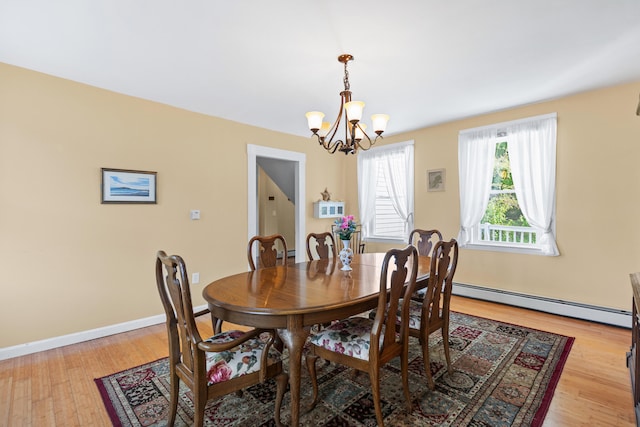 dining room featuring a baseboard radiator, light hardwood / wood-style flooring, and an inviting chandelier