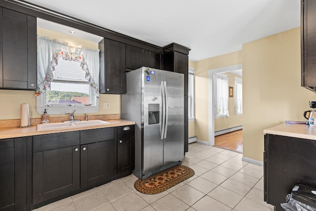 kitchen with sink, stainless steel fridge with ice dispenser, light tile patterned floors, and a baseboard heating unit