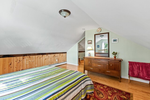 bedroom featuring light wood-type flooring, a baseboard radiator, and vaulted ceiling