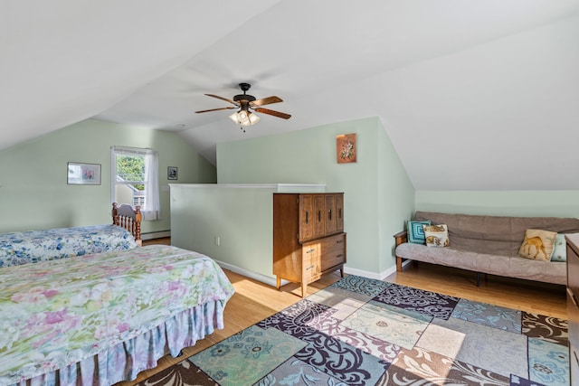 bedroom featuring baseboard heating, light wood-type flooring, ceiling fan, and vaulted ceiling