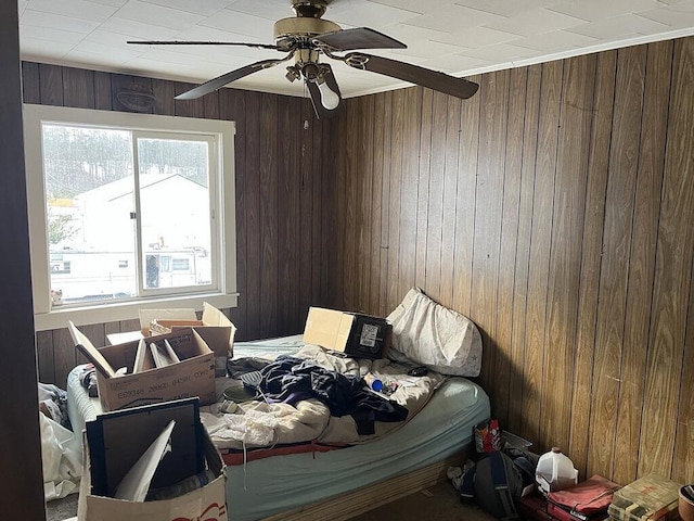 bedroom with ceiling fan and wooden walls