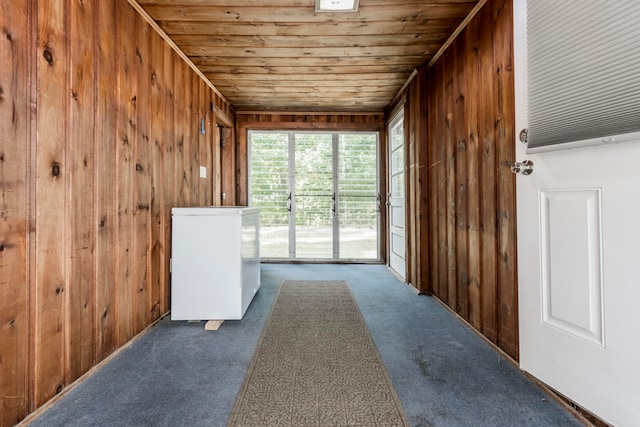 interior space featuring wood ceiling, dark colored carpet, and wood walls